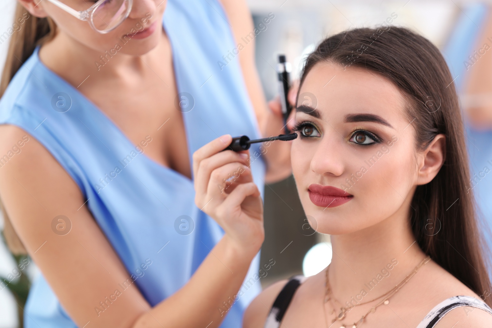 Photo of Professional visage artist applying makeup on woman's face in salon