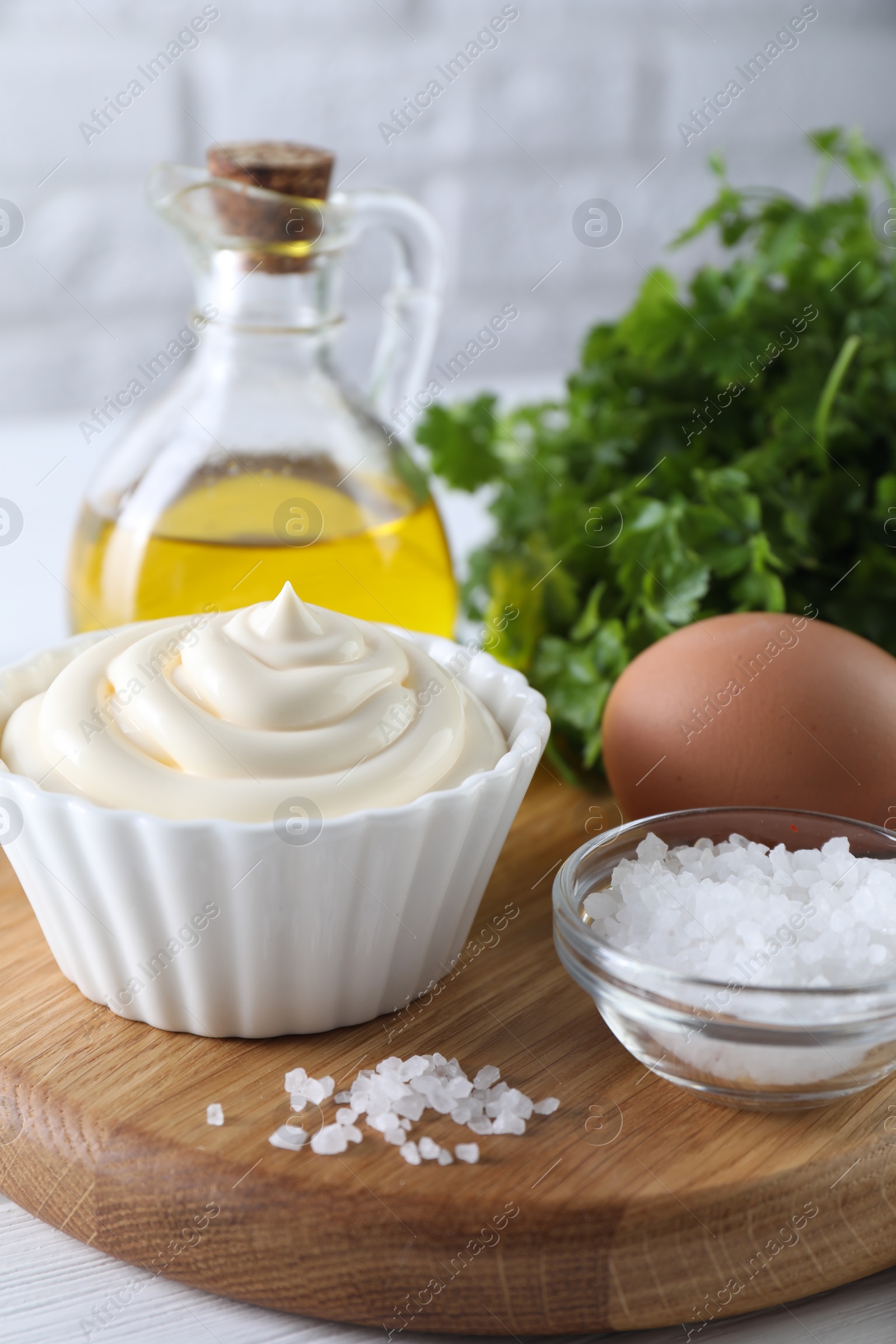 Photo of Fresh mayonnaise sauce in bowl and ingredients on table