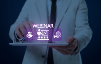Webinar. Man holding tablet on dark blue background, closeup. Virtual screen with icons over computer