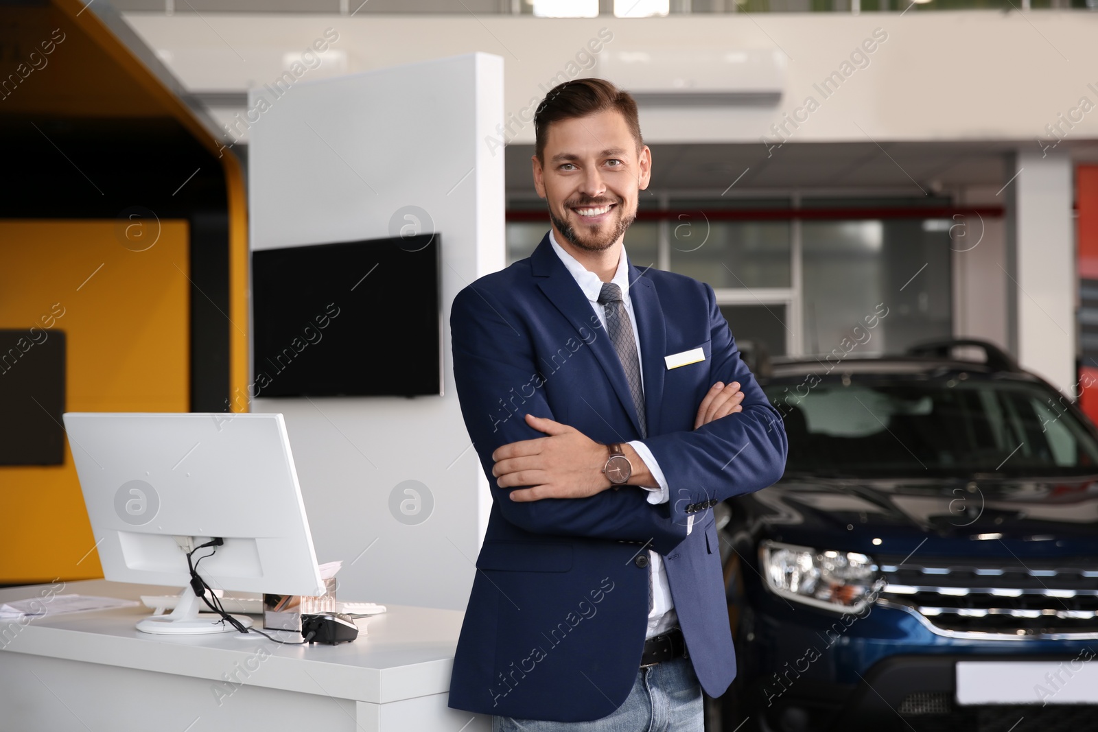 Photo of Salesman standing in modern auto dealership. Buying new car