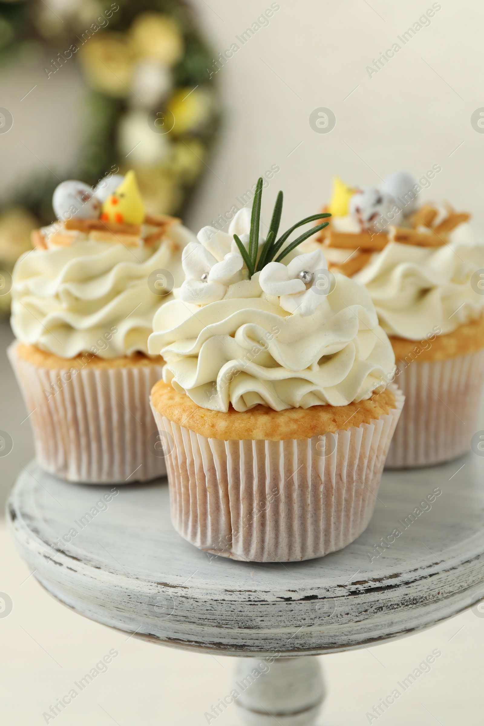 Photo of Tasty Easter cupcakes with vanilla cream on dessert stand, closeup