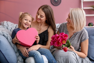 Photo of Happy young woman with her mother and daughter at home