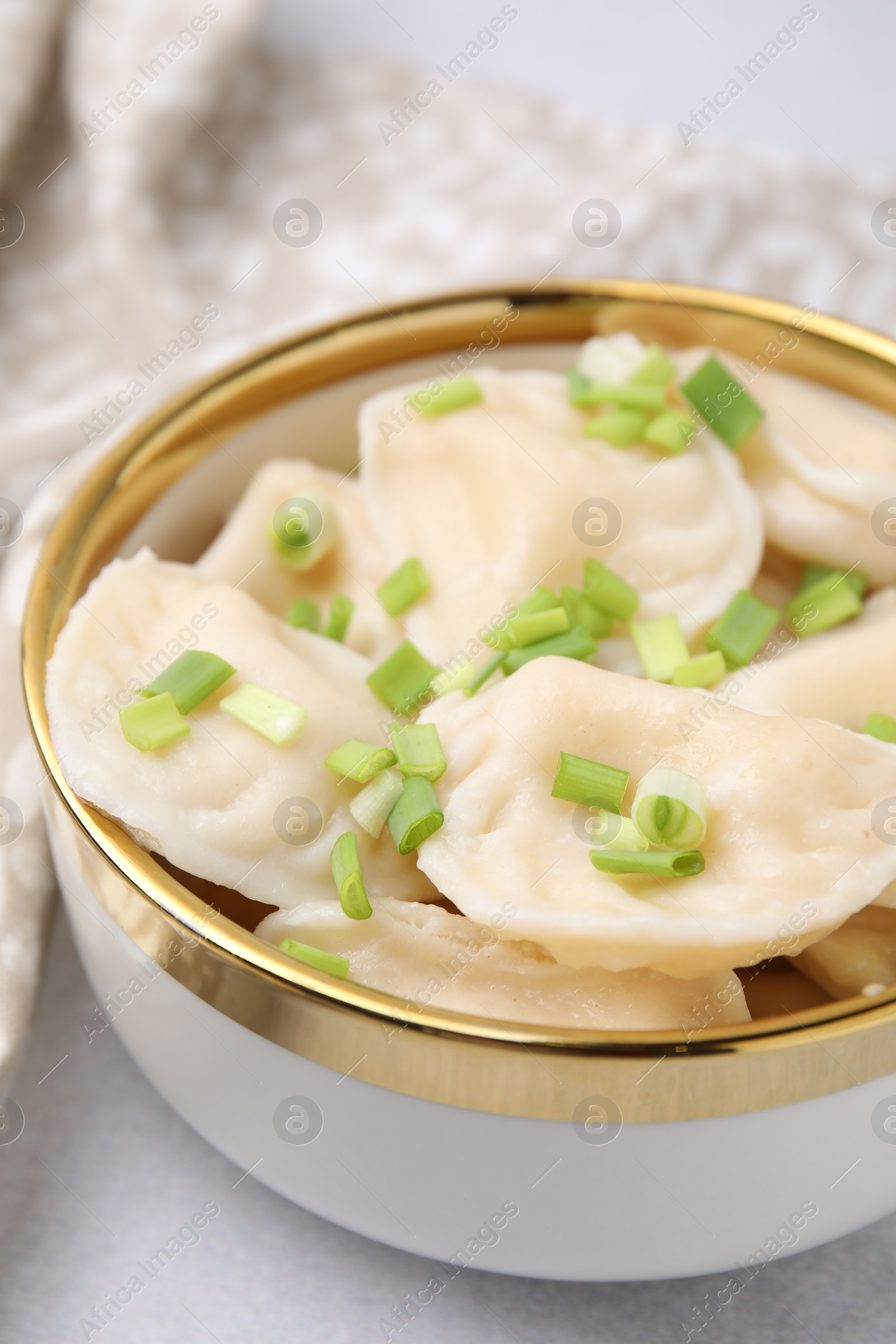 Photo of Cooked dumplings (varenyky) with tasty filling and green onion on light table, closeup