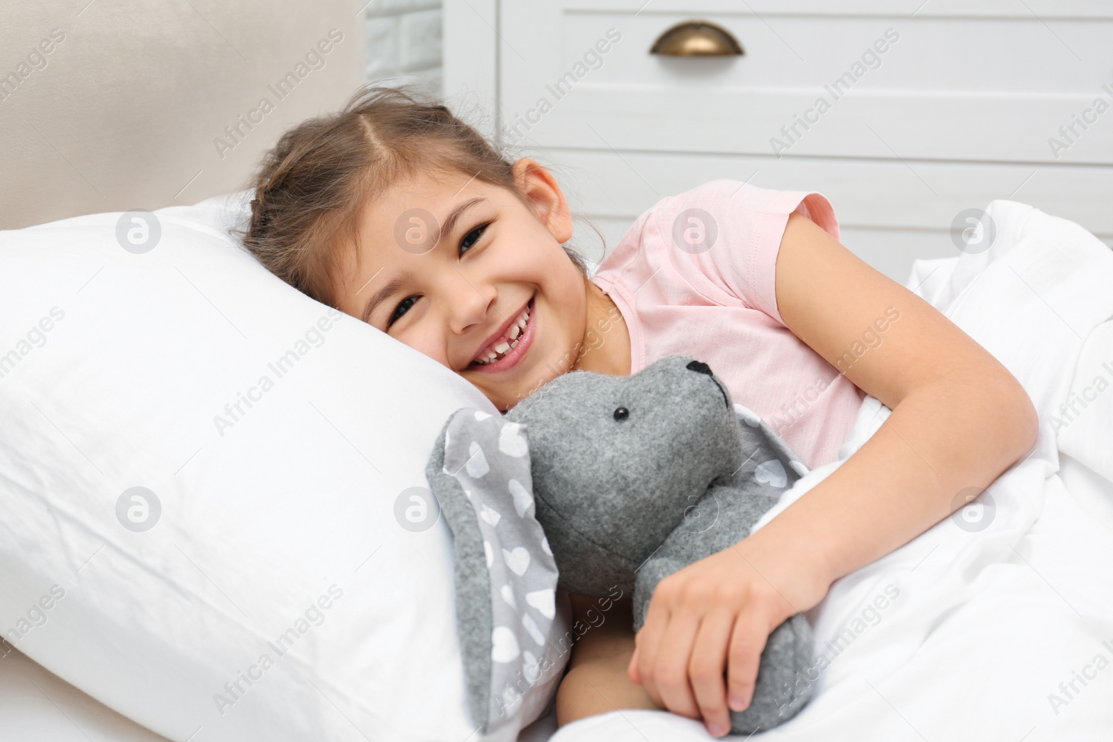 Photo of Cute child with stuffed rabbit resting in bed at hospital