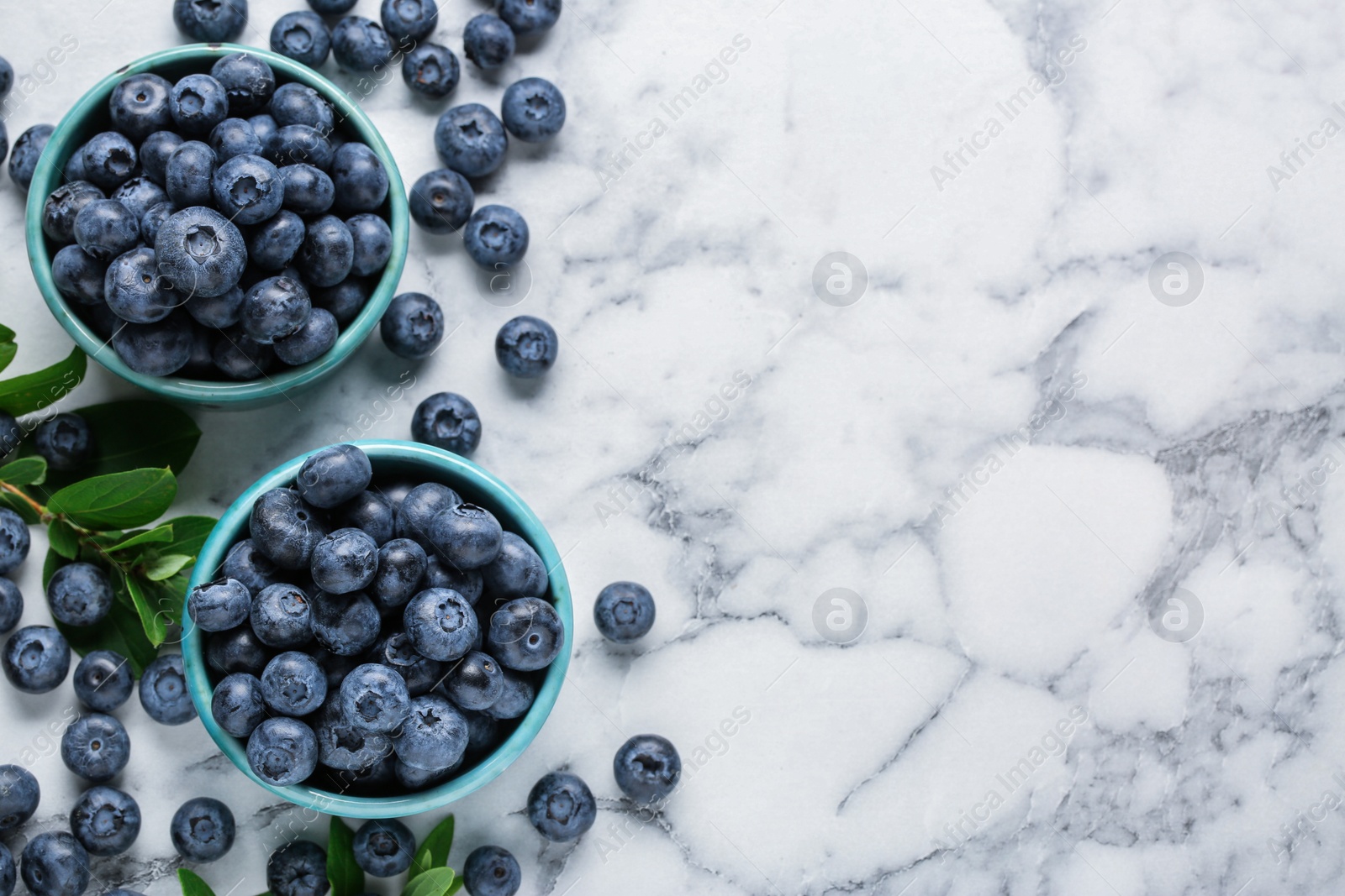 Photo of Tasty fresh blueberries on white marble table, flat lay. Space for text