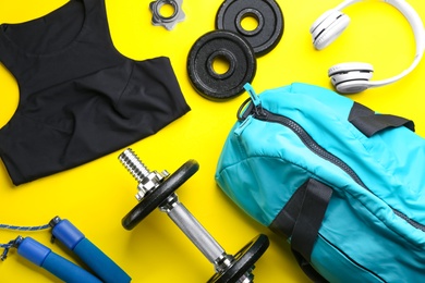 Photo of Flat lay composition with gym bag and sportswear on yellow background
