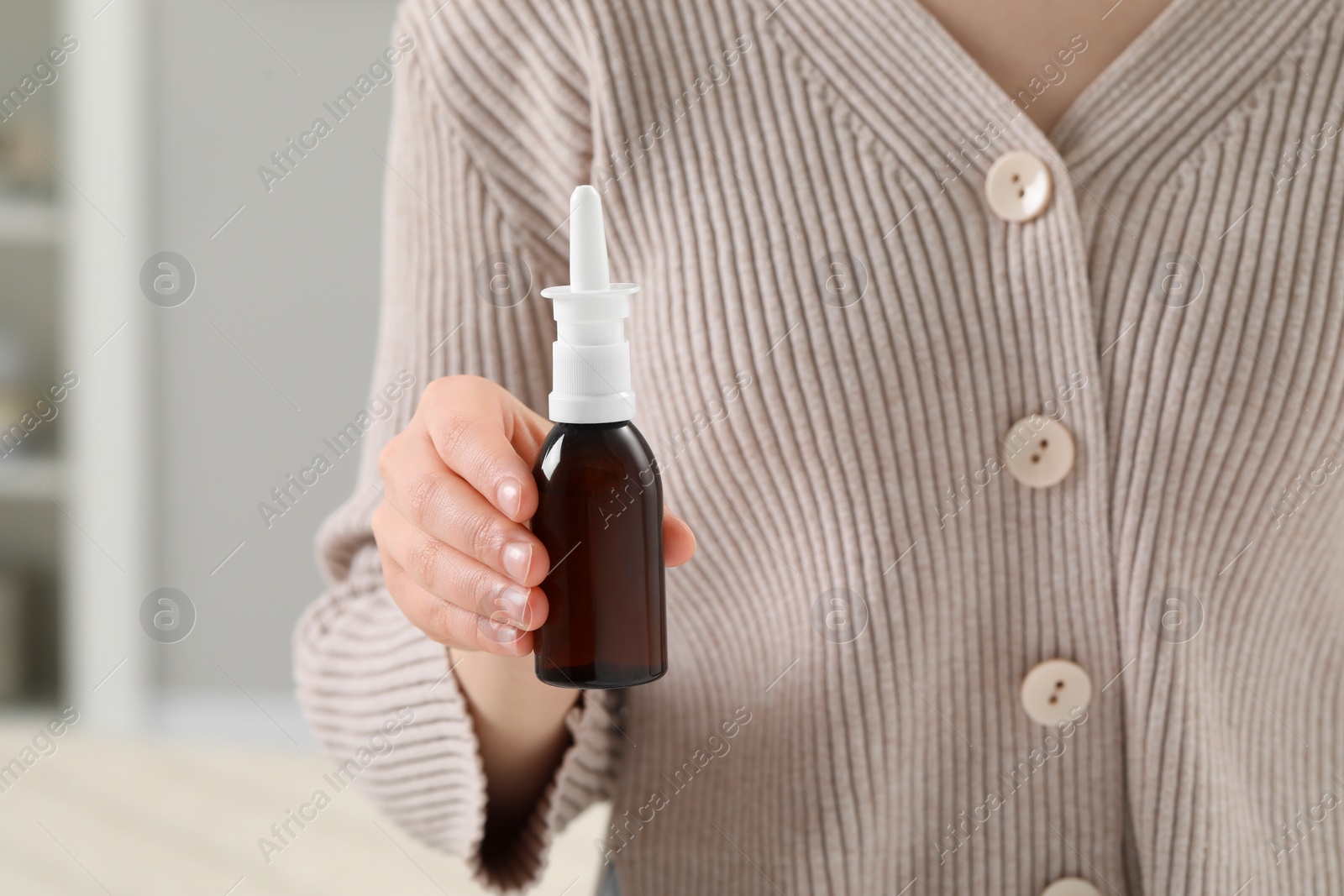 Photo of Woman holding nasal spray indoors, closeup view