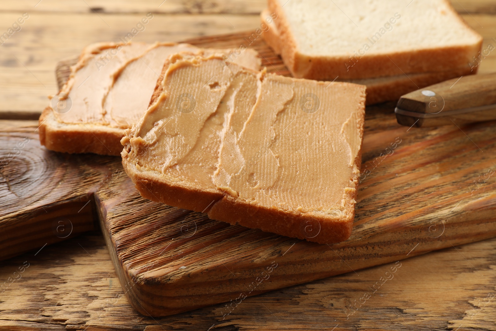 Photo of Tasty peanut butter sandwiches on wooden table, closeup view