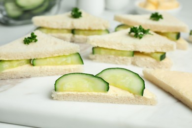Tasty sandwiches with cucumber, butter and parsley on white table, closeup
