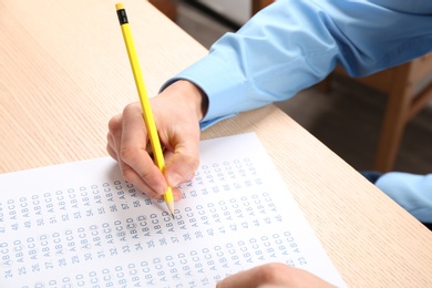 Photo of Student filling answer sheet at table, closeup