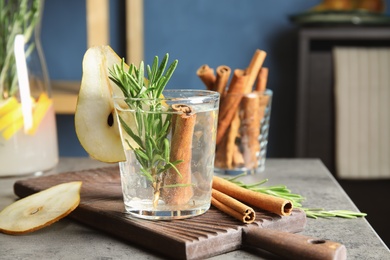 Photo of Tasty refreshing cocktail with rosemary and cinnamon on table