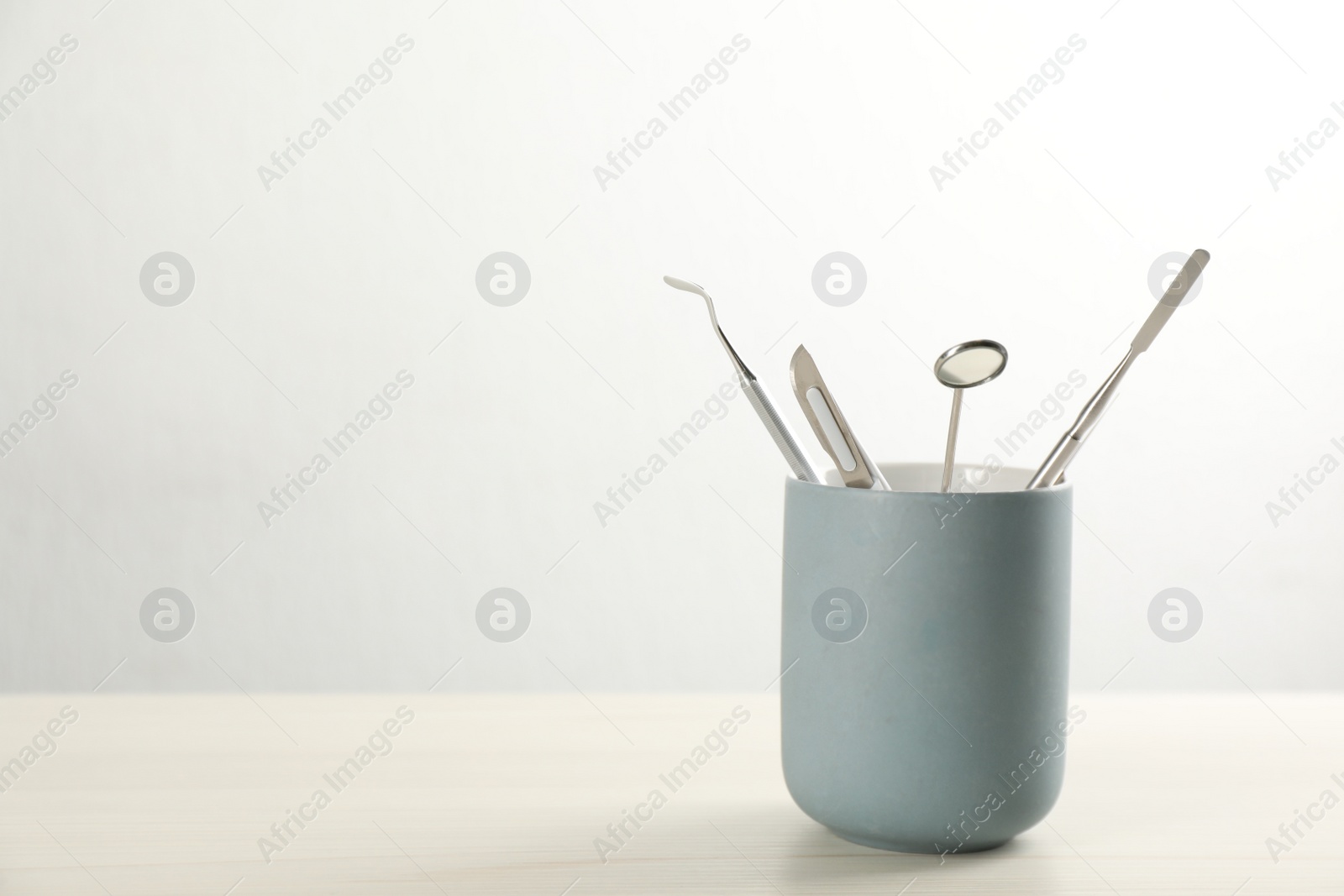 Photo of Holder with set of dentist's tools on wooden table. Space for text