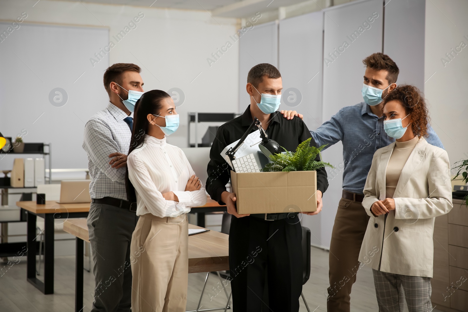 Photo of Coworkers saying goodbye to dismissed man in office