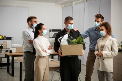 Coworkers saying goodbye to dismissed man in office