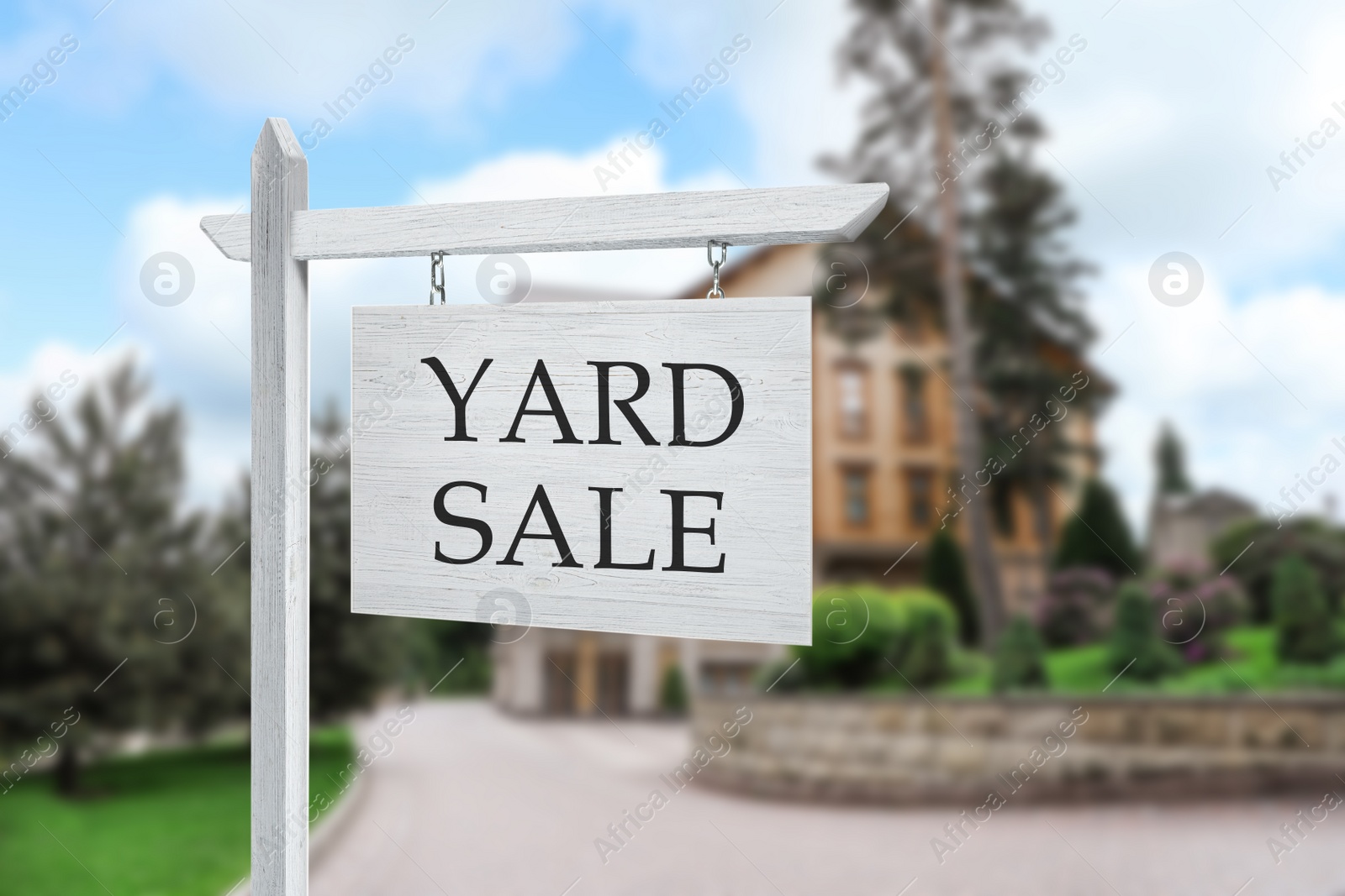 Image of Sign with text YARD SALE and blurred view of beautiful house