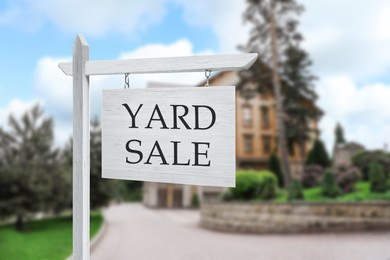 Image of Sign with text YARD SALE and blurred view of beautiful house