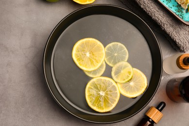Photo of Flat lay composition with essential oil and lemons on grey table. Aromatherapy treatment