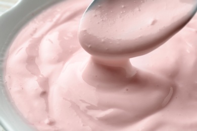 Photo of Bowl and spoon with tasty yogurt, closeup