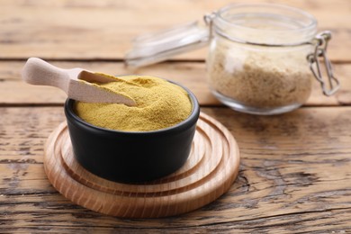 Bowl and scoop of granulated brewer`s yeast on wooden table