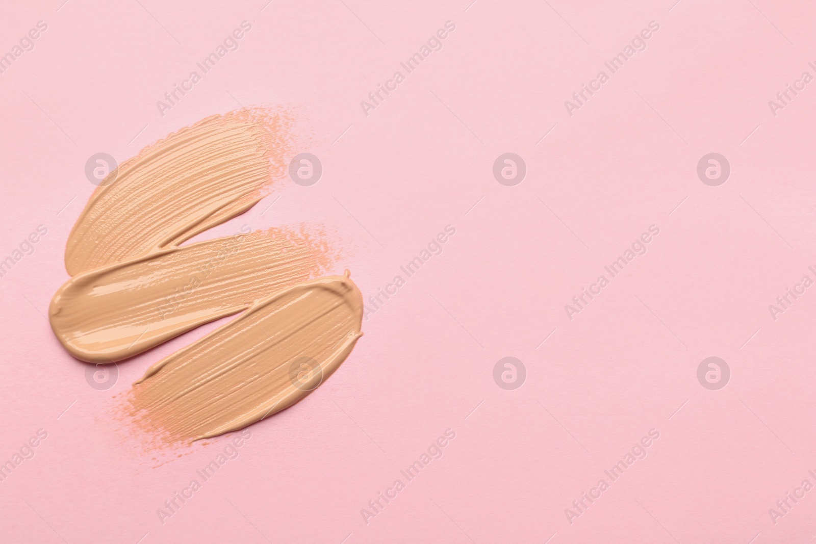 Photo of Sample of liquid skin foundation on pink background, top view. Space for text