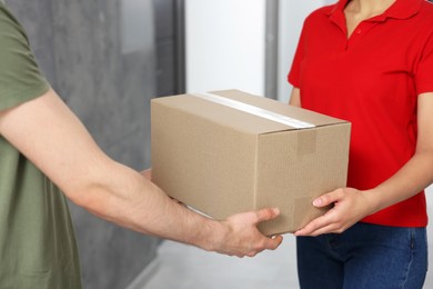 Photo of Courier giving parcel to customer in hallway, closeup