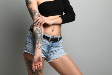 Photo of Beautiful woman with tattoos on body against grey background, closeup. Space for text