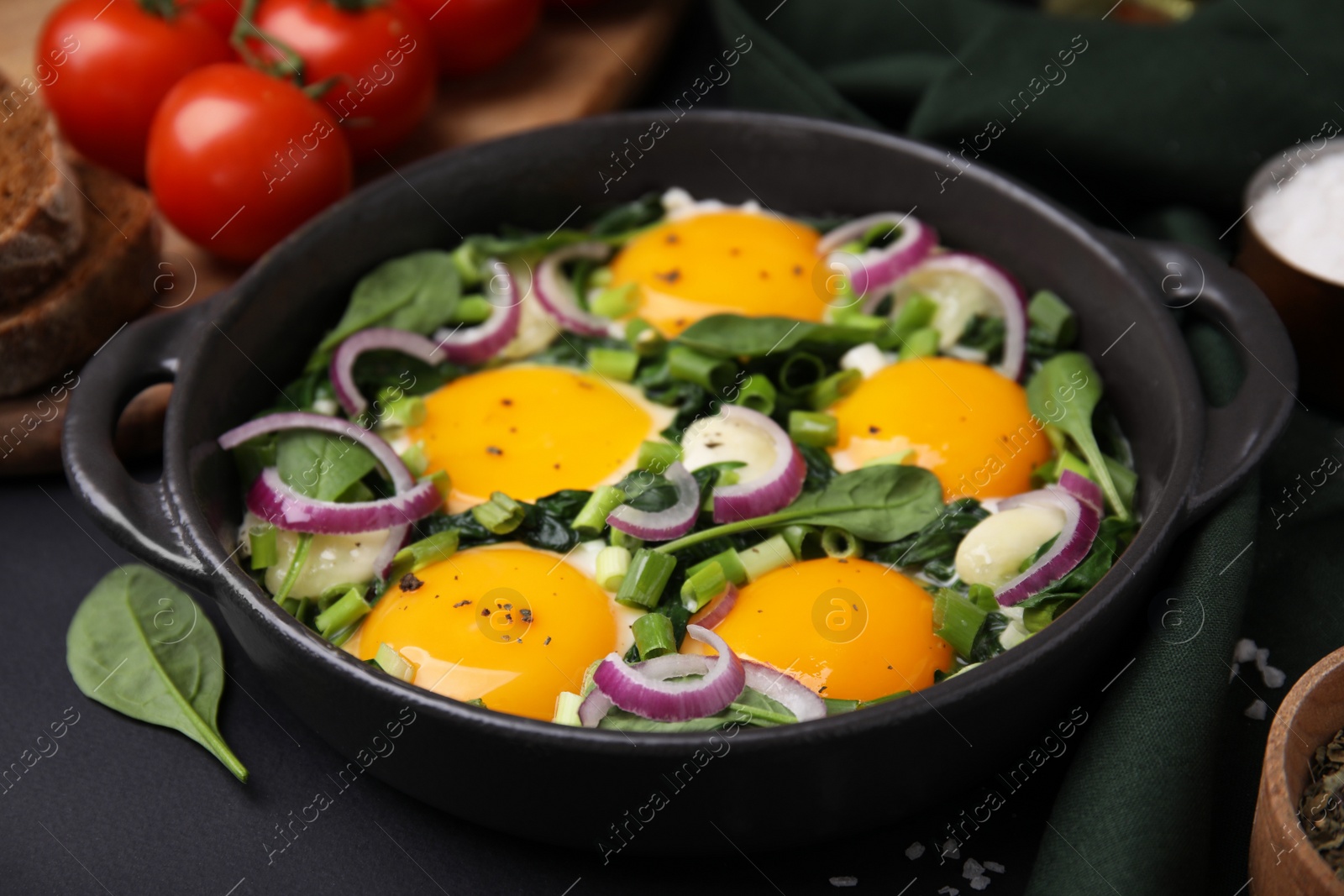 Photo of Tasty green Shakshouka served on black table, closeup