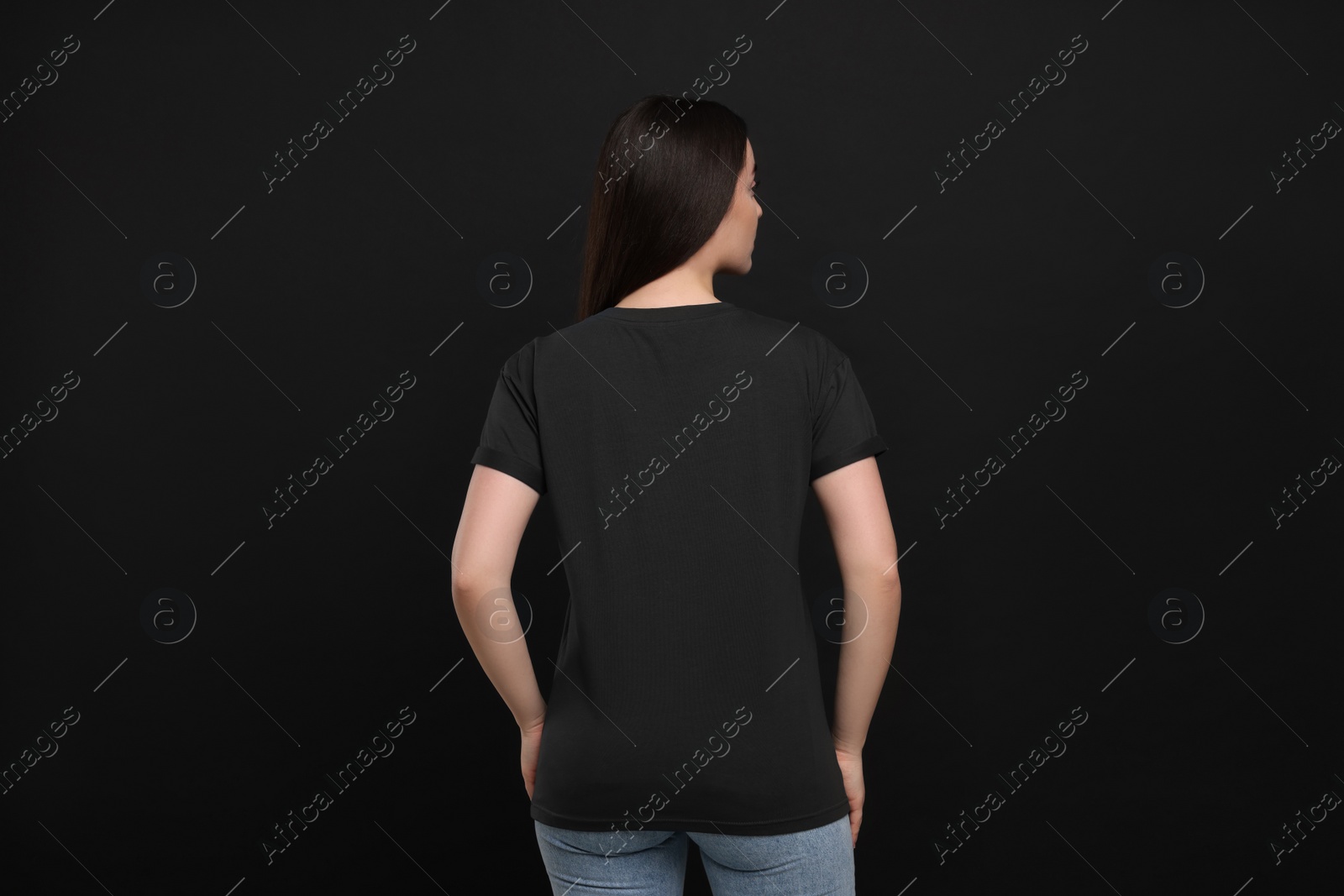 Photo of Woman wearing black t-shirt on dark background, back view