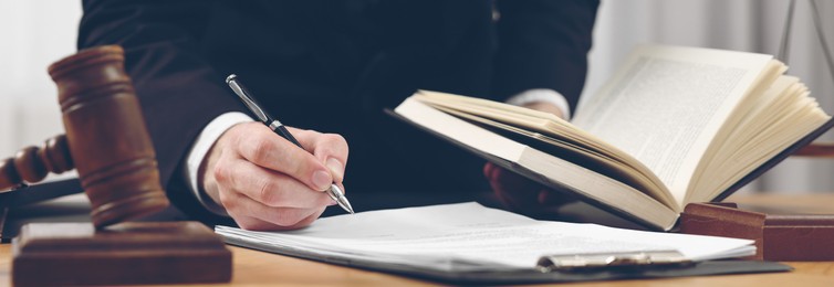 Lawyer working with document at table in office, closeup. Banner design