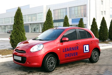 Image of Modern red car L-plate sign on city street