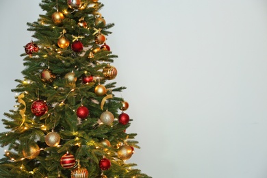 Beautiful Christmas tree with fairy lights and festive decor on white background