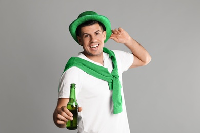 Photo of Happy man in St Patrick's Day outfit with beer on light grey background