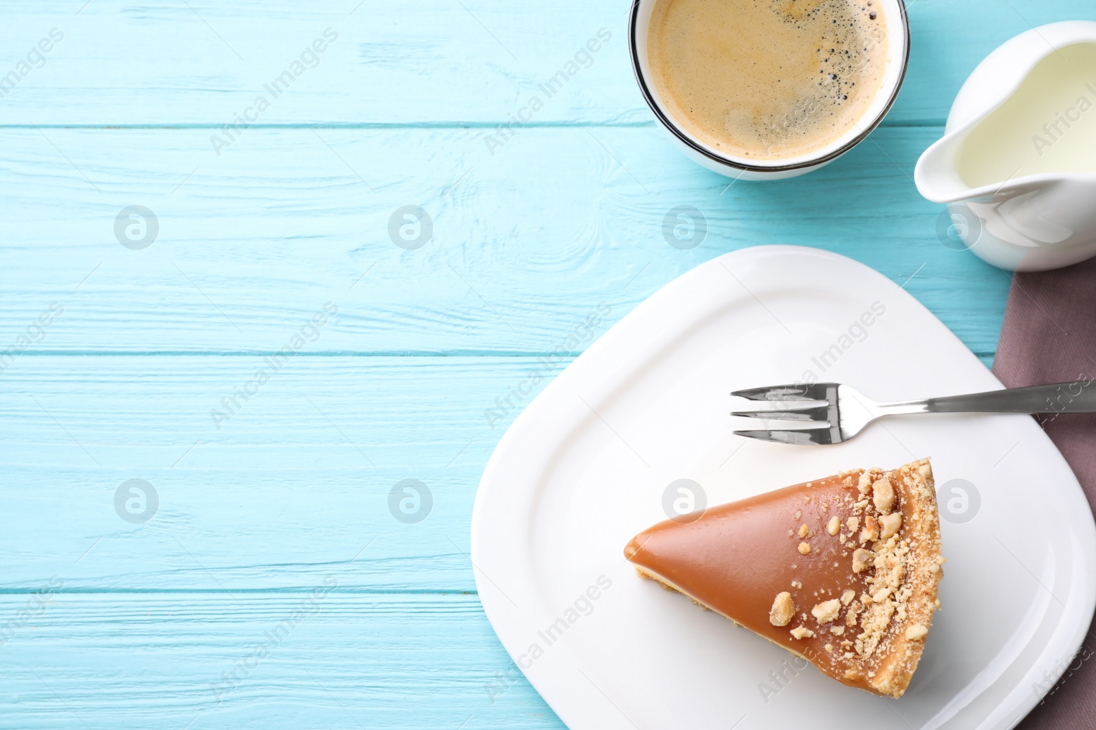 Photo of Piece of delicious cake with caramel served on light blue wooden table, flat lay. Space for text