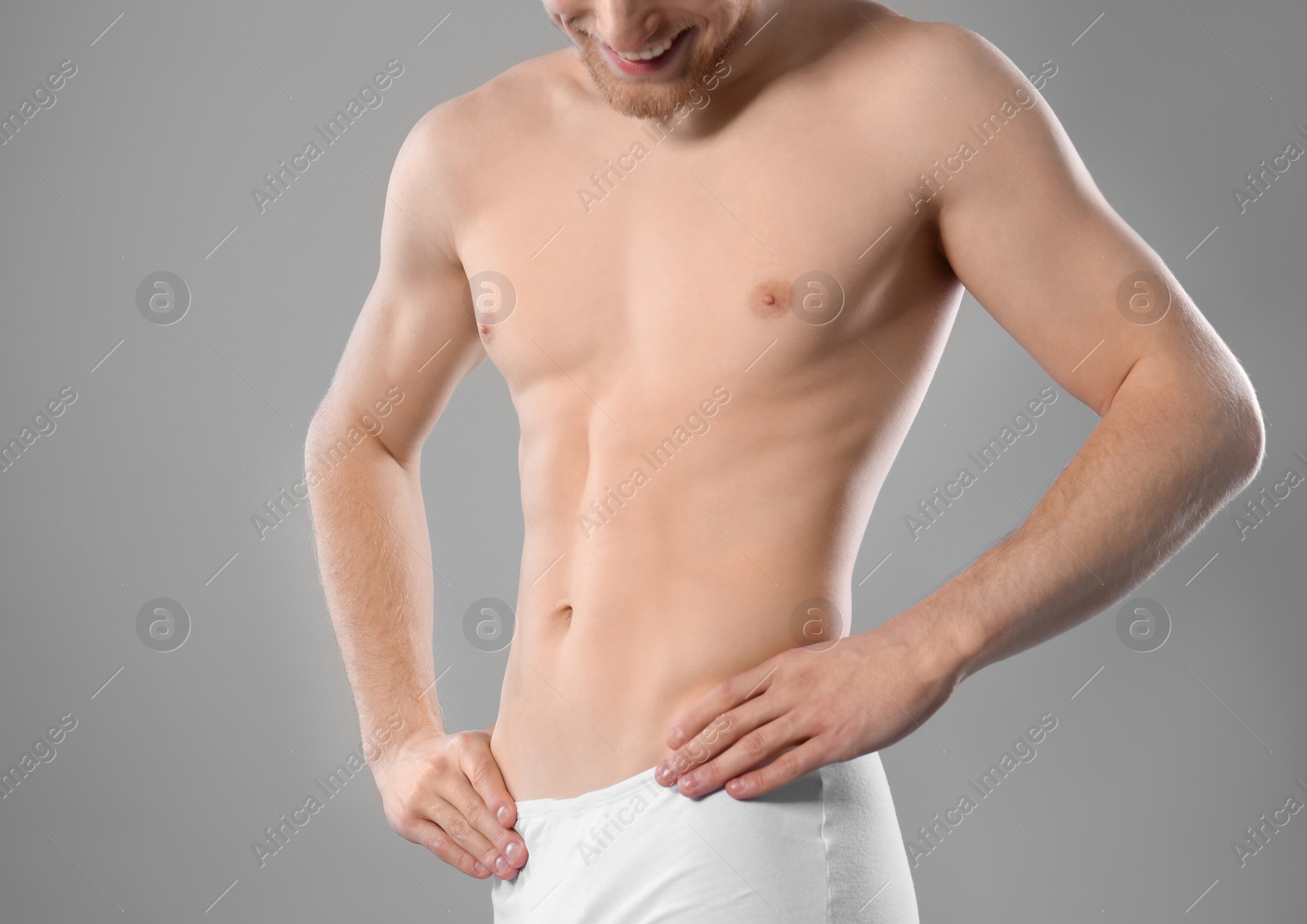 Photo of Young man with slim body on grey background, closeup