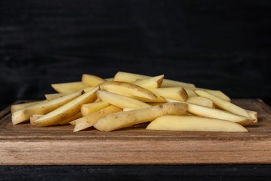 Photo of Cut raw potatoes on black wooden table, closeup