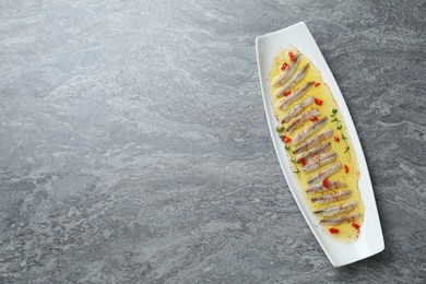 Photo of Tasty pickled anchovies with spices on gray table, top view. Space for text