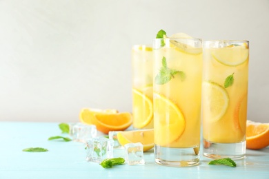 Photo of Glasses of citrus refreshing drink on light blue wooden table, space for text