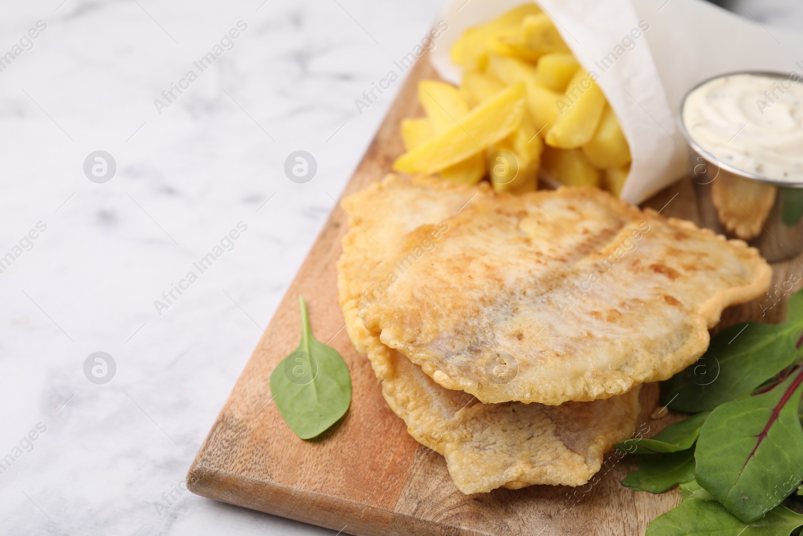 Photo of Delicious fish and chips with tasty sauce and mangold on white marble table, closeup. Space for text