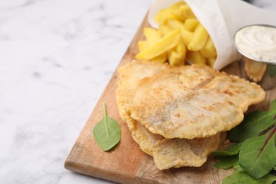 Photo of Delicious fish and chips with tasty sauce and mangold on white marble table, closeup. Space for text