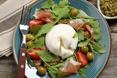 Photo of Delicious burrata salad served on wooden table, flat lay