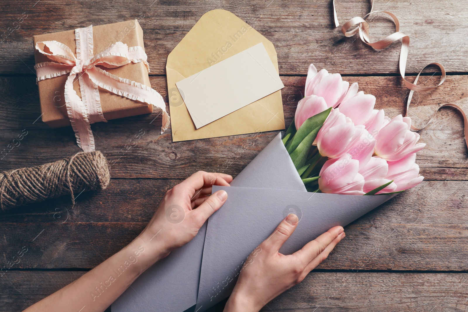 Photo of Female florist creating beautiful tulip bouquet for Mother's Day at table