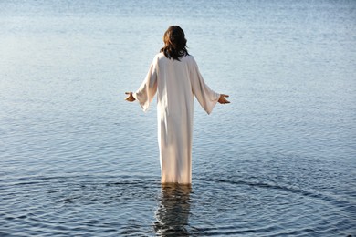 Photo of Jesus Christ in water lit by morning sun, back view