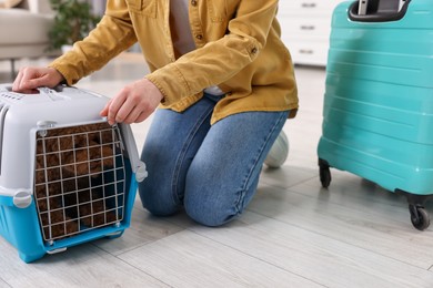Woman closing carrier with her pet before travelling indoors, closeup
