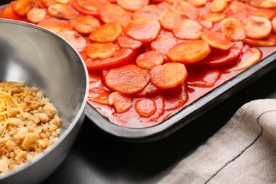 Tasty parsnips with sauce and ingredients on dark grey textured table, closeup