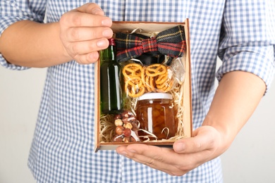 Photo of Man holding box with stylish craft gift set on light grey background, closeup