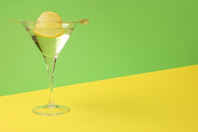 Martini glass of refreshing cocktail with lemon slice on color background, space for text
