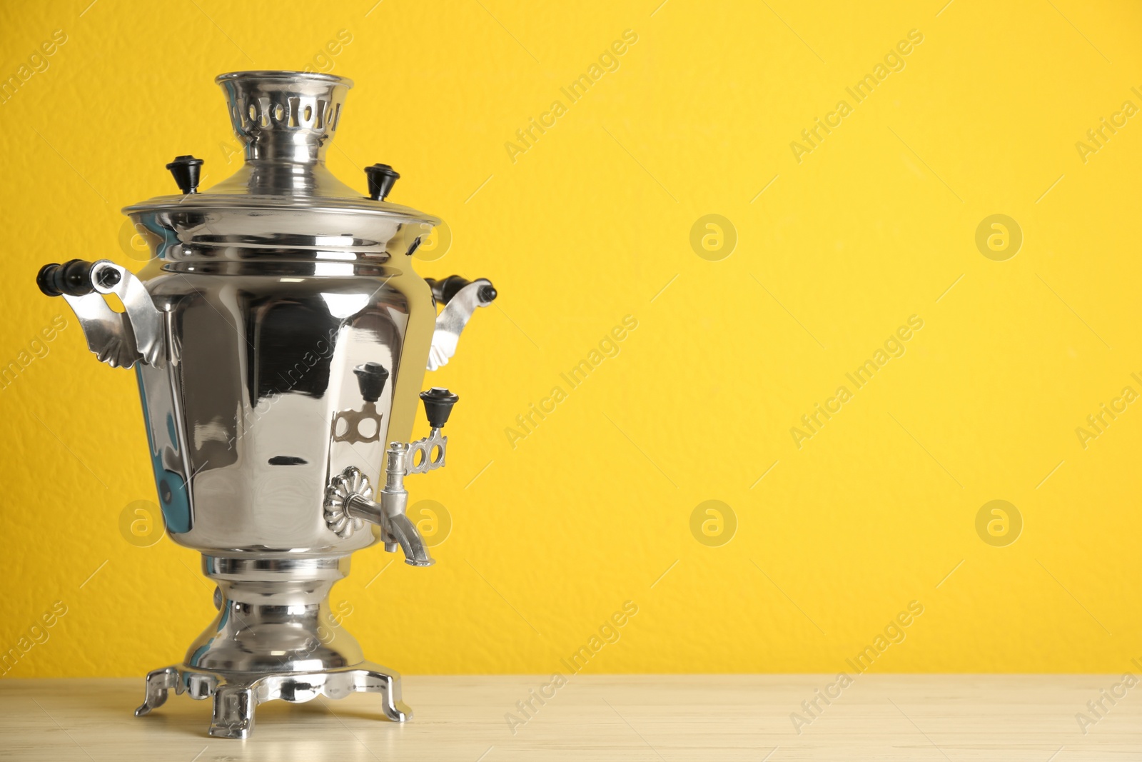 Photo of Traditional Russian samovar on yellow background. Space for text