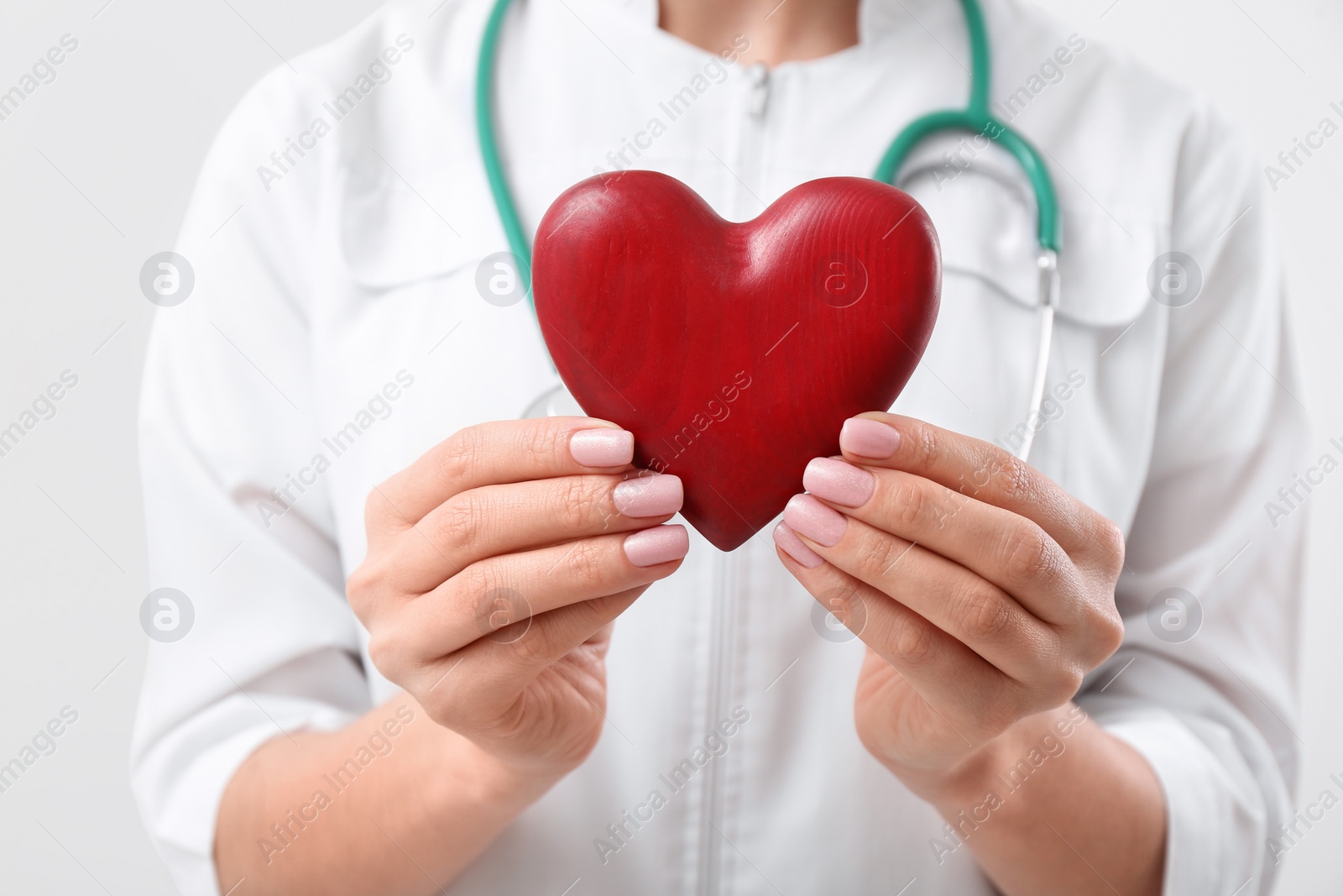 Photo of Doctor holding red heart on white background, closeup. Cardiology concept