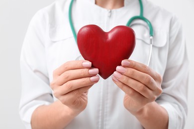 Photo of Doctor holding red heart on white background, closeup. Cardiology concept