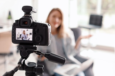 Photo blogger recording video indoors, selective focus on camera display. Space for text